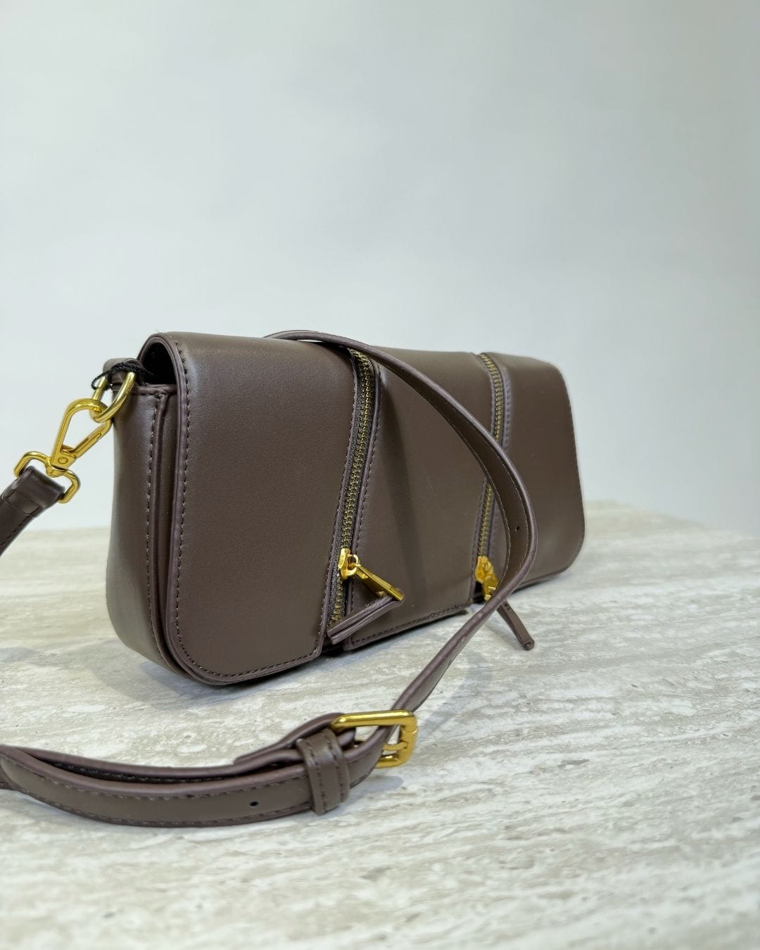 Brown crossbody bag with gold details on display