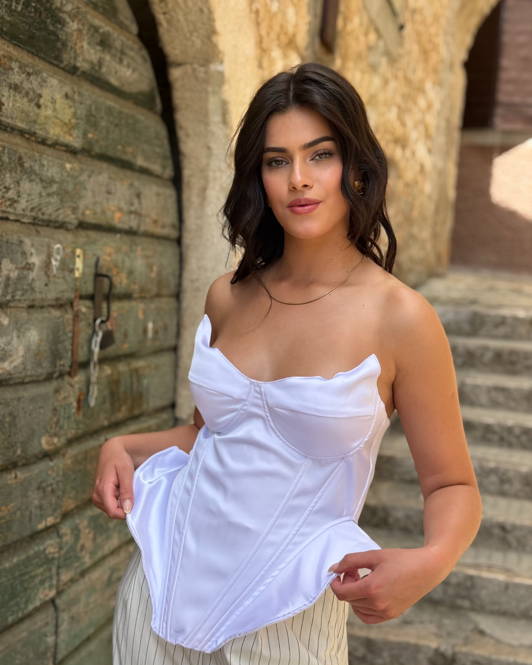 Model nosi elegantni bijeli korzet satenskog izgleda.