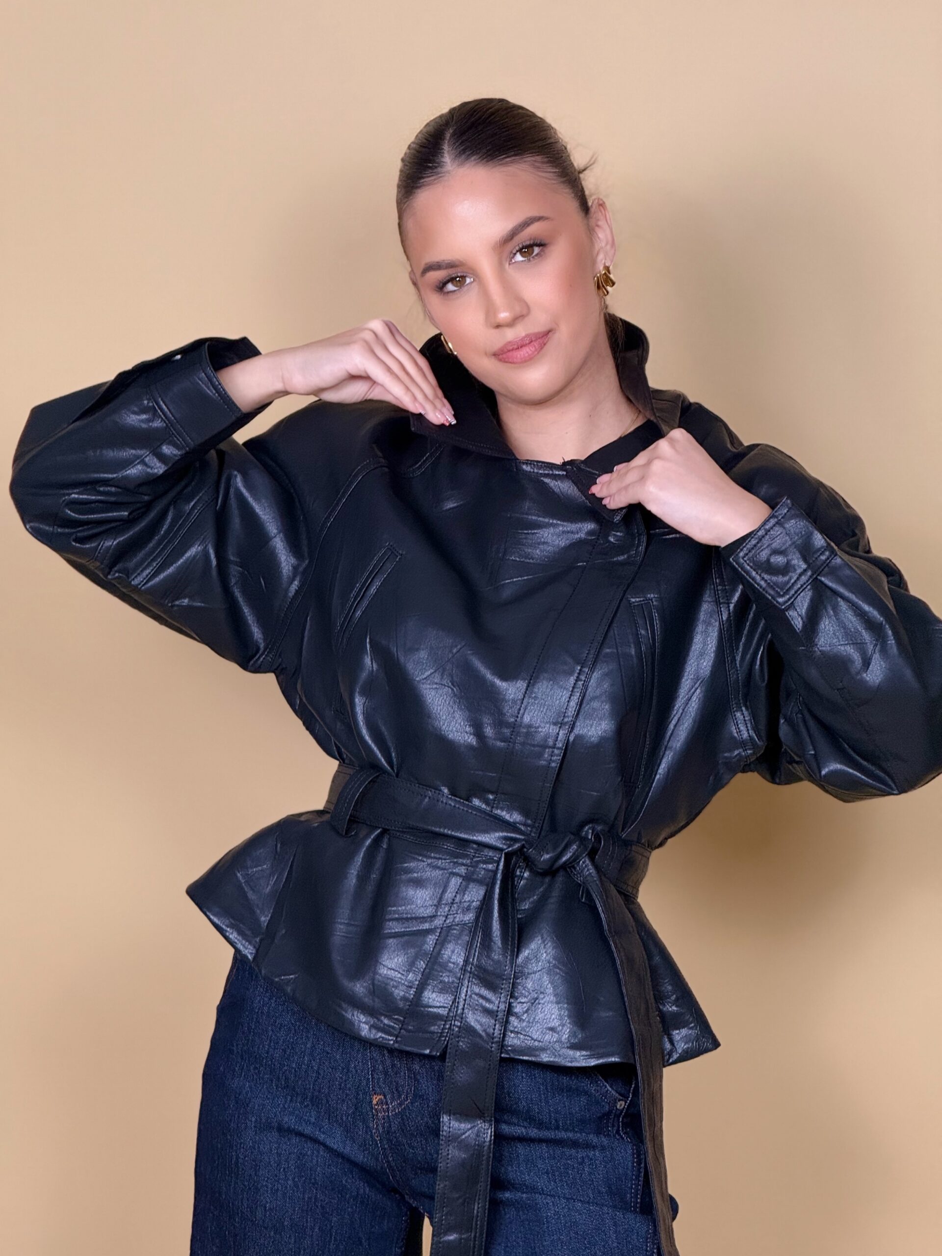 Model nosi žensku crnu jaknu Midnight Icon kožnog izgleda s klasičnim ovratnikom i pojasom.
