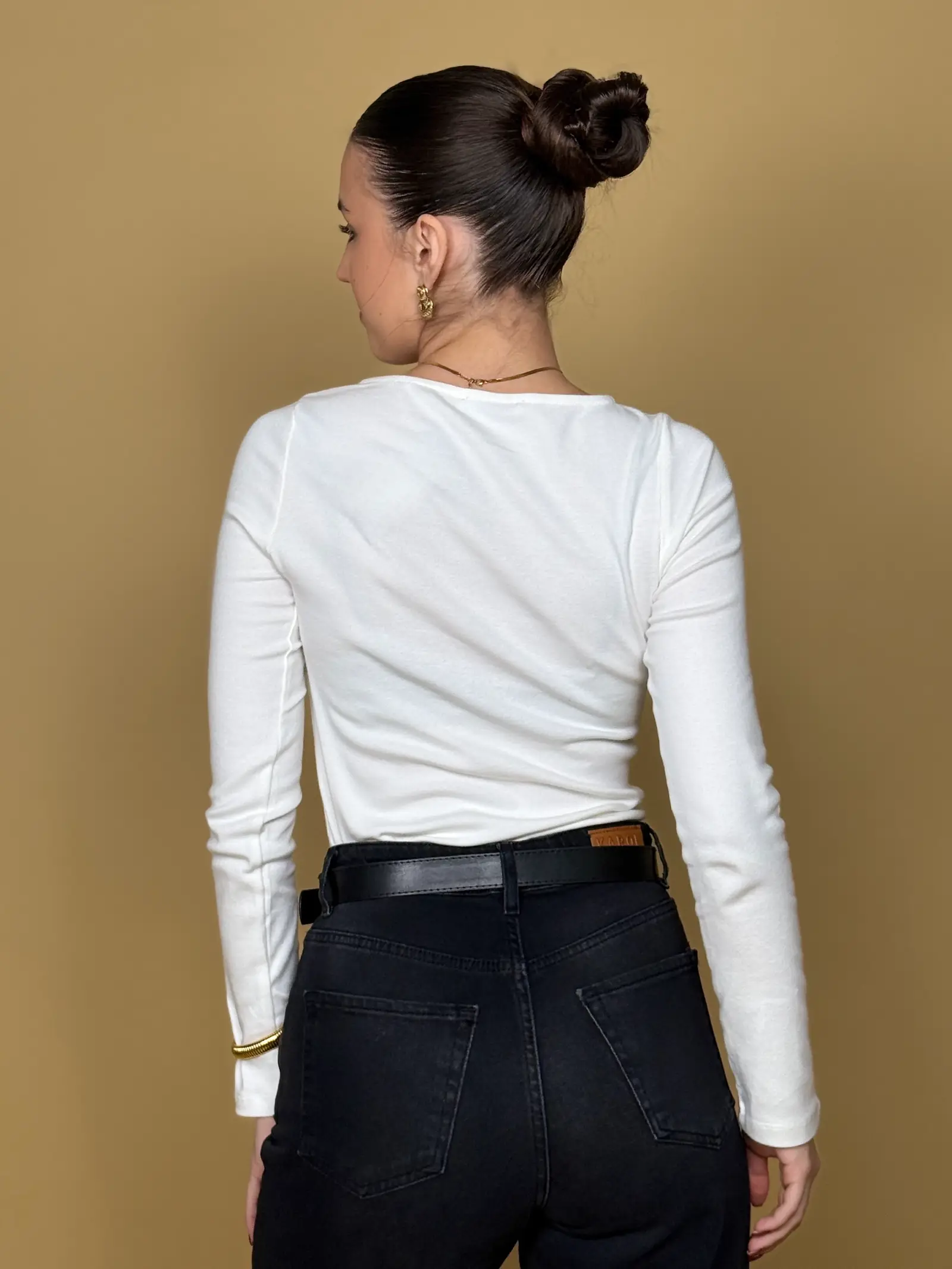 Model nosi žensku bijelu majicu Alessia dugih rukava s patentnim zatvaračem sprijeda.