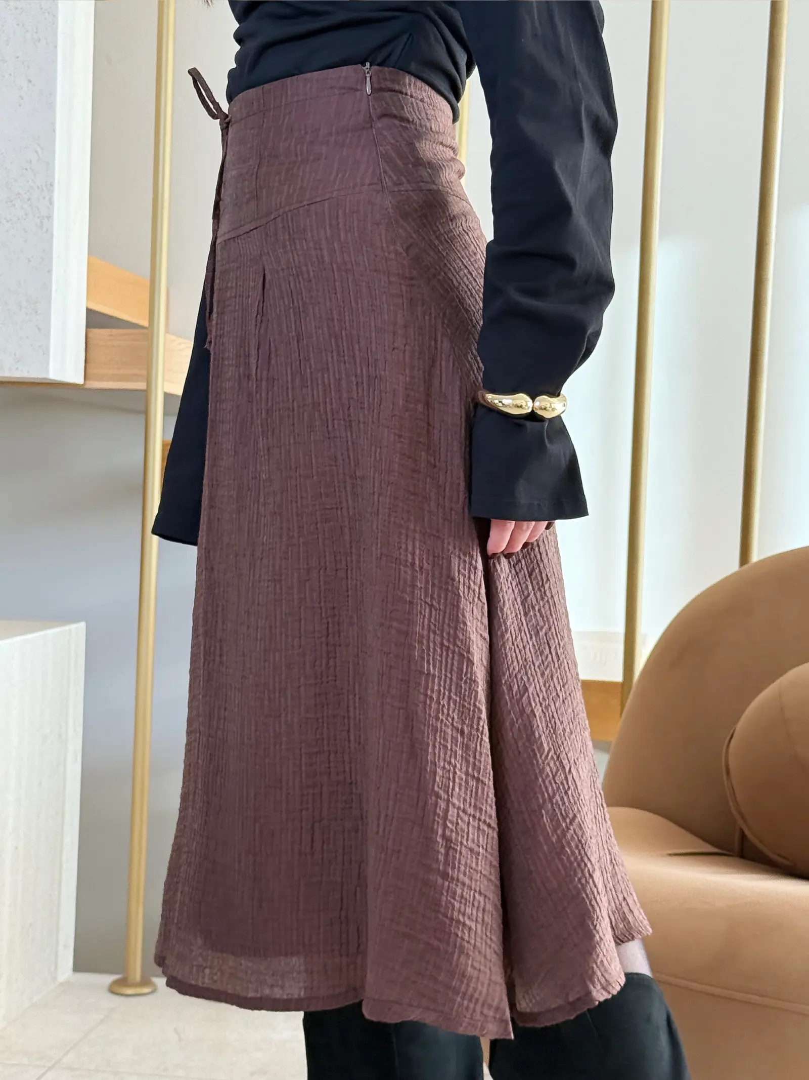 Model nosi žensku smeđu suknju Odette visokog struka, duge i blago proširene siluete.