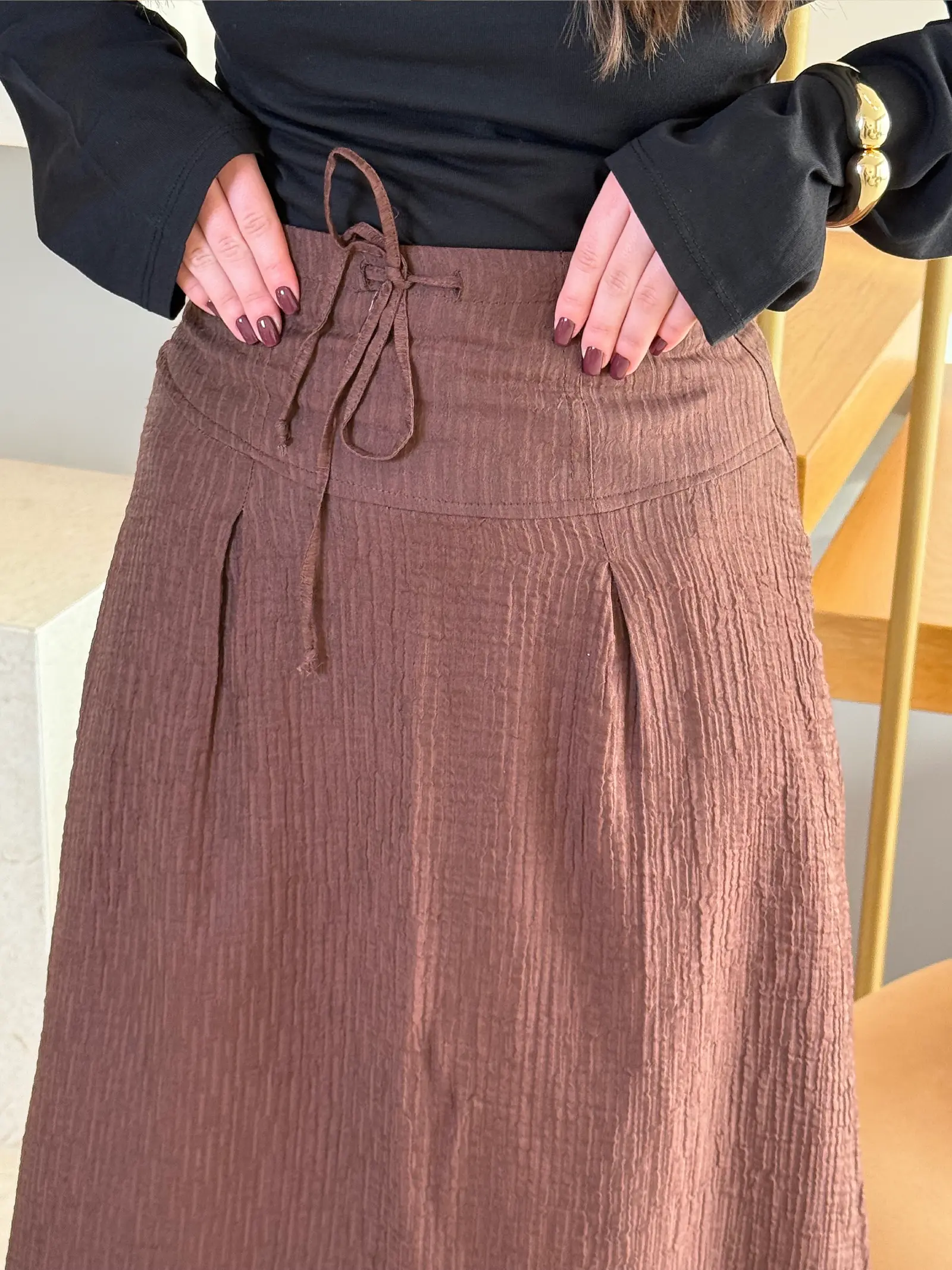 Model nosi žensku smeđu suknju Odette visokog struka, duge i blago proširene siluete.