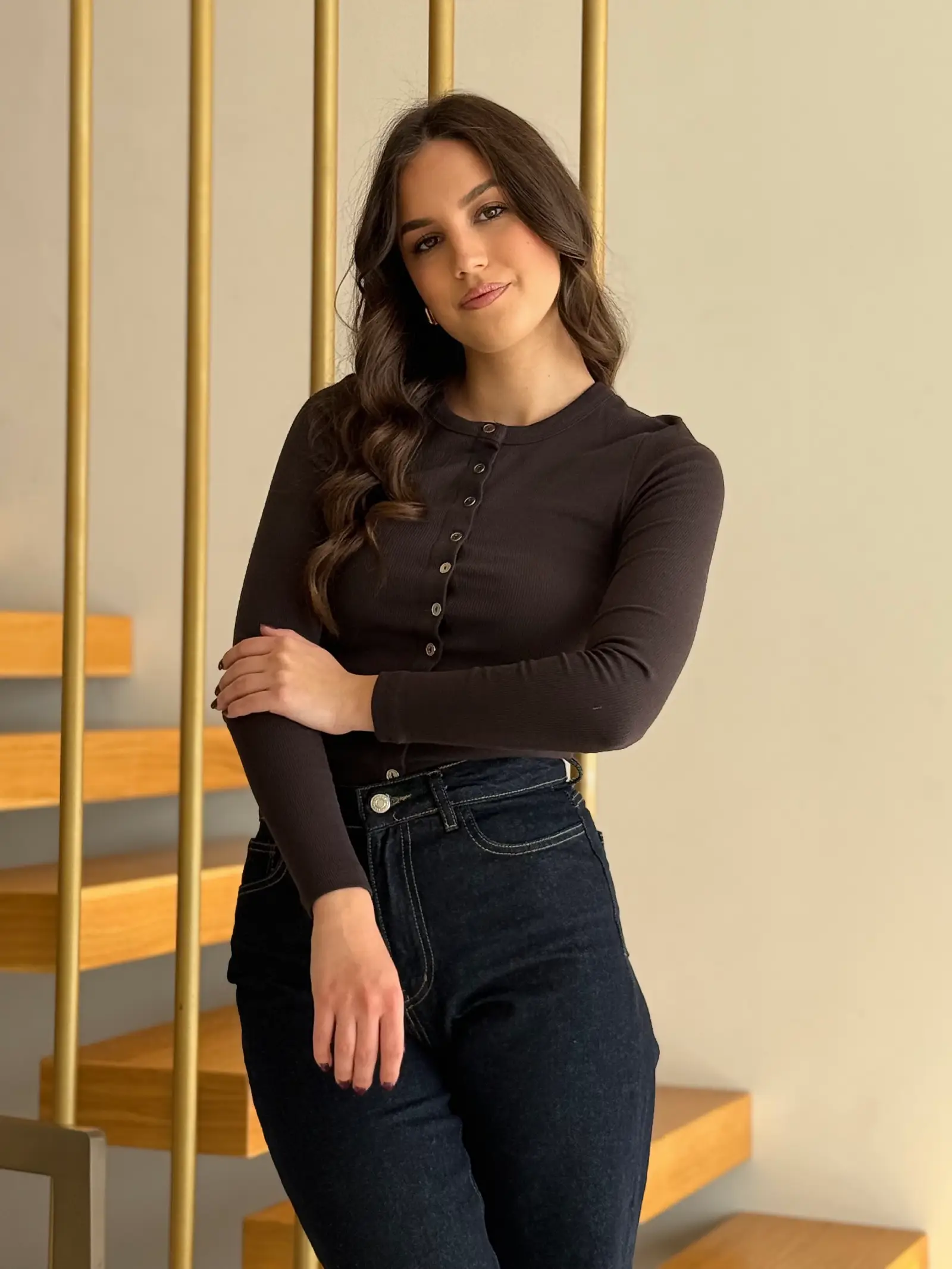 Model nosi žensku smeđu majicu Aurelia pripijenog kroja, dugih rukava i s gumbima sprijeda.