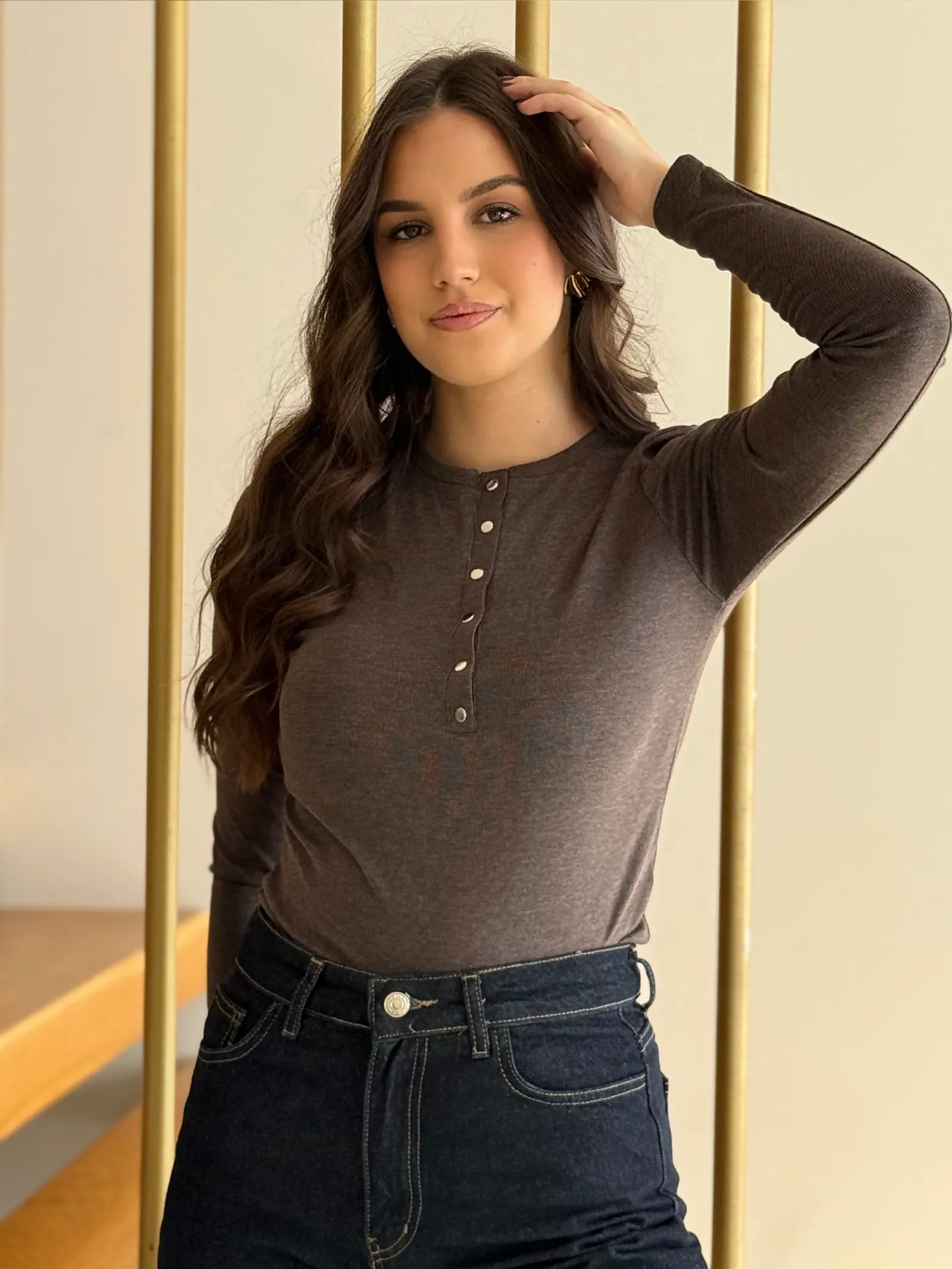 Model nosi žensku smeđu majicu Juliette pripijenog kroja, dugih rukava i s ukrasnim gumbima sprijeda.
