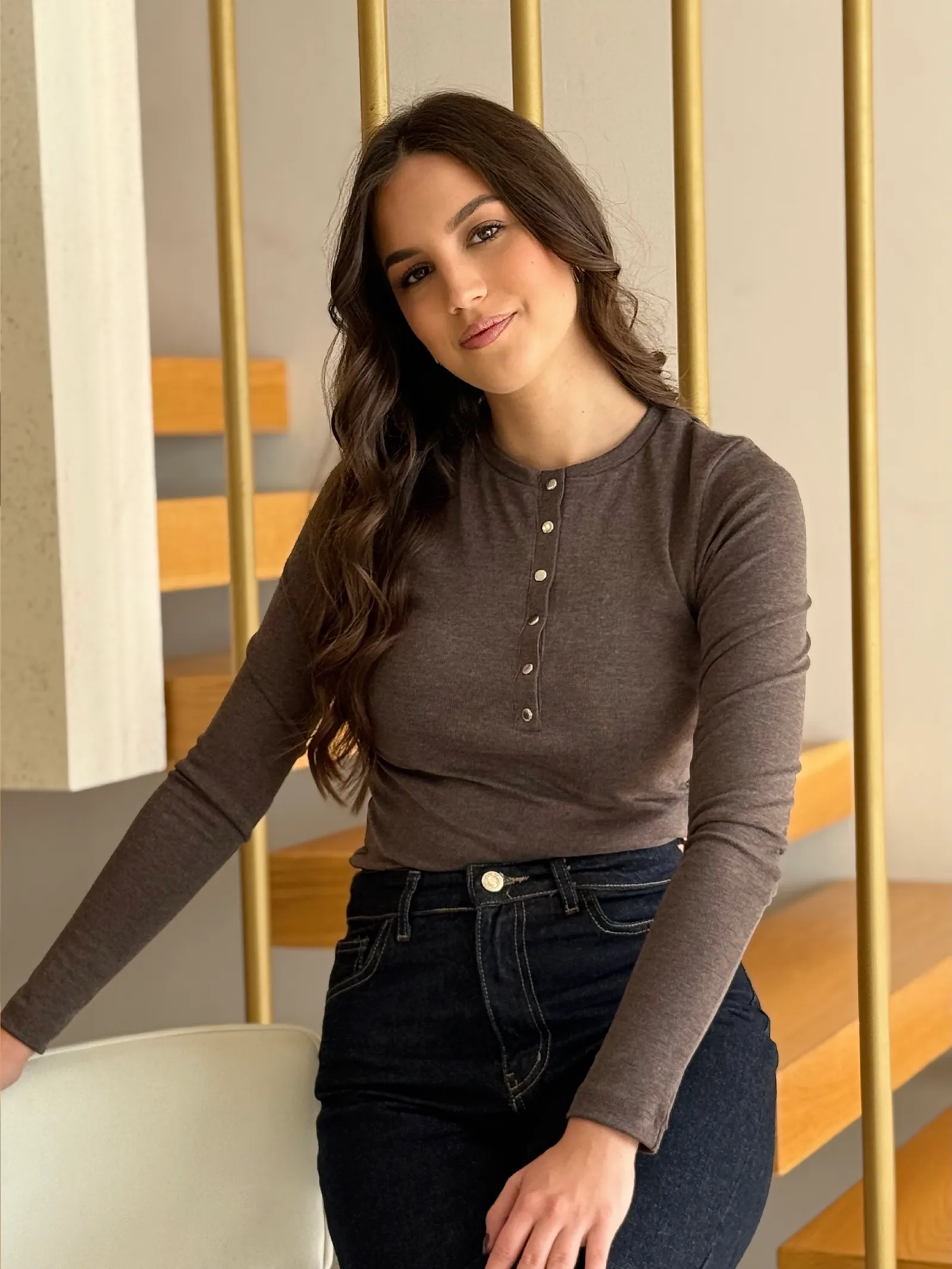 Model nosi žensku smeđu majicu Juliette pripijenog kroja, dugih rukava i s ukrasnim gumbima sprijeda.