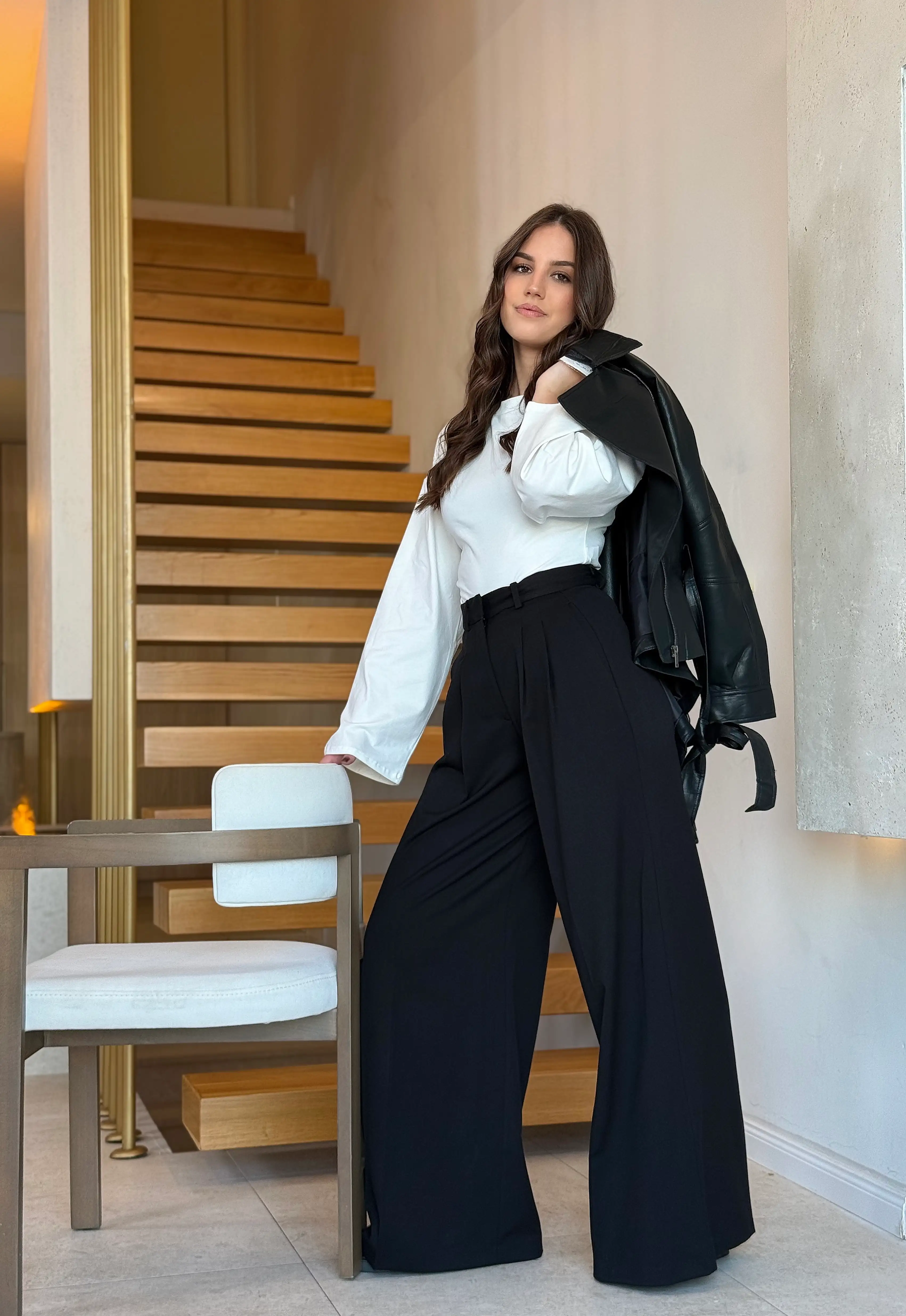 Model nosi ženske crne hlače Marcella visokog struka s dugim širokim nogavicama.