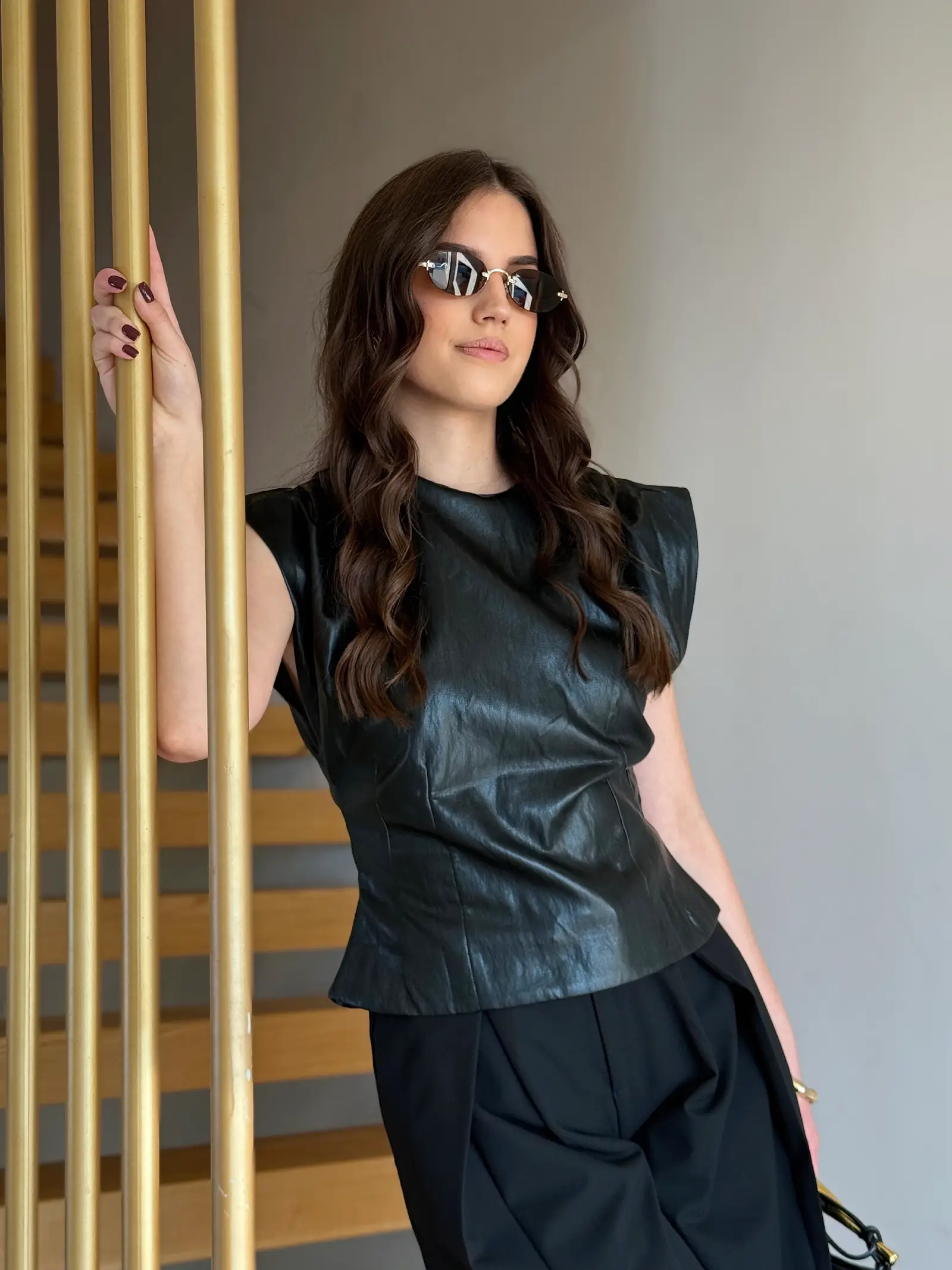 Model nosi ženski crni top Vivienne kožnog izgleda, pripijenog kroja i s naglašenim ramenima.