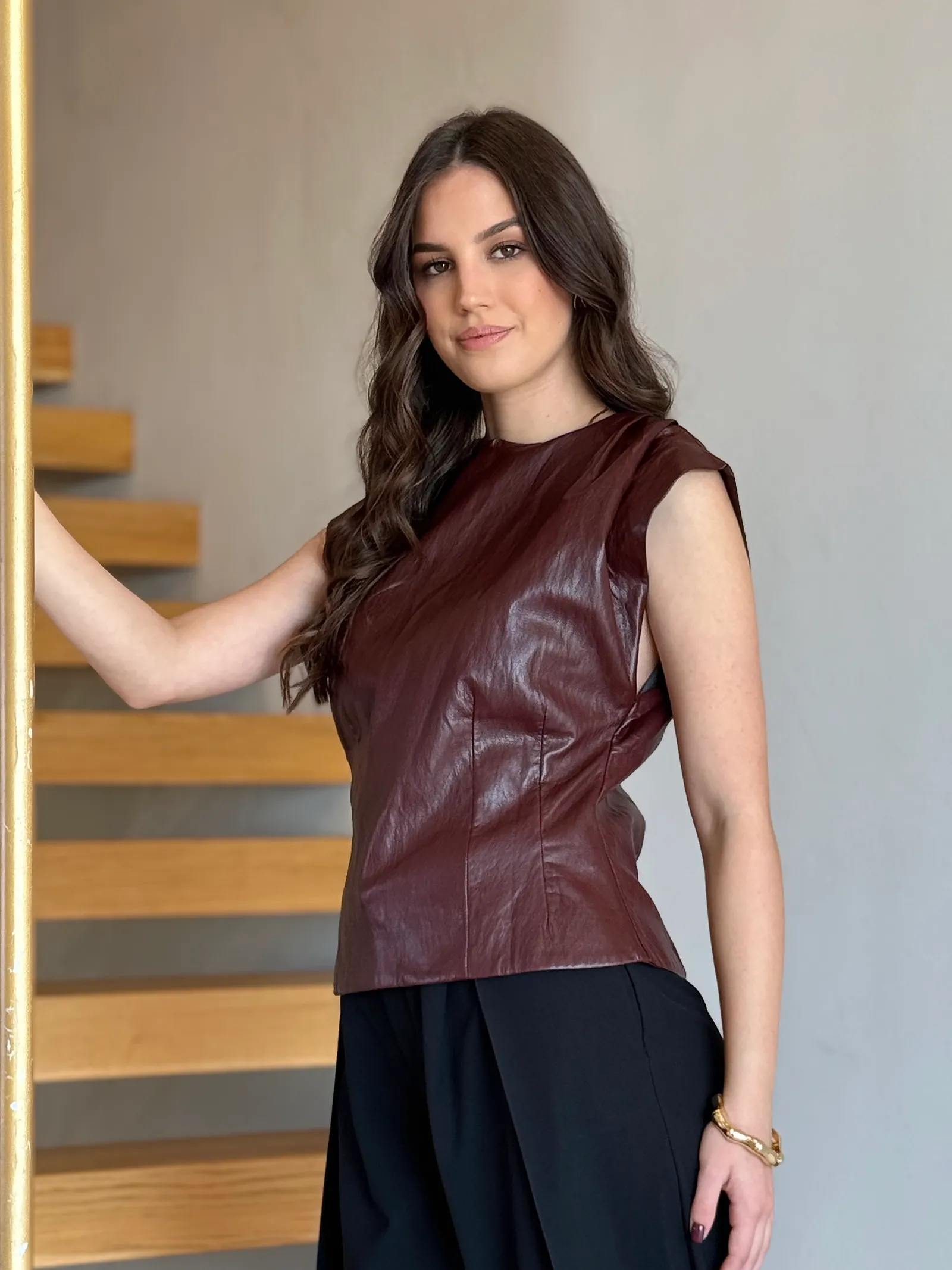 Model nosi ženski bordo top Vivienne kožnog izgleda, pripijenog kroja i s naglašenim ramenima.